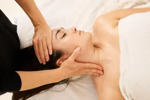 Woman receiving a gentle facial massage around the temples