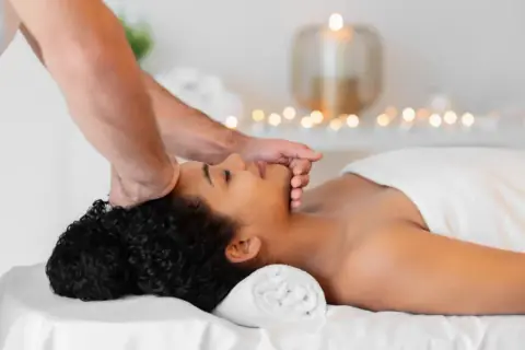 Therapist massaging a woman’s jawline in a modern spa room