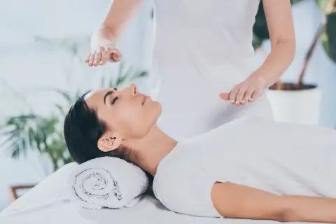 Calm woman lying down while hands are held over her head during Reiki