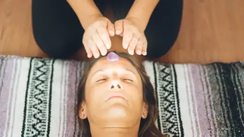 Therapist giving a Reiki treatment with stones placed along the body