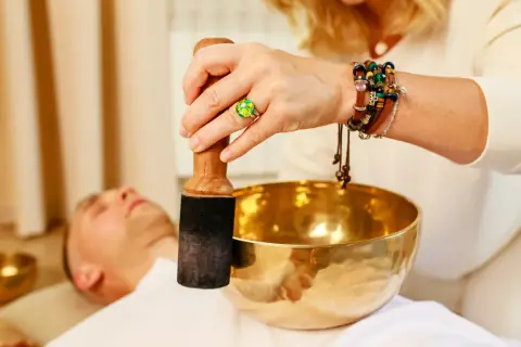 Practitioner playing a singing bowl with a mallet